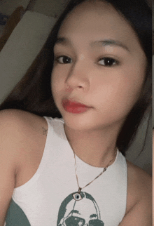 a woman wearing a white tank top and a necklace