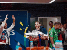 a man holds a trophy in front of a wall that says champions league