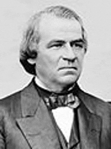 a black and white photo of a man wearing a suit and bow tie .