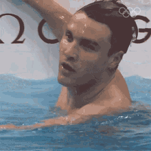 a man in a swimming pool with the olympic rings on the wall