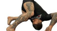 a man with a tattoo on his leg is wearing a black shirt with a red triangle on the front