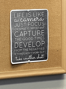 a sign on a cork board that says life is like a camera