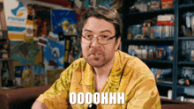 a man wearing glasses and a yellow shirt with the word oooohhh on it