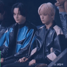 a couple of young men are sitting next to each other in a stadium .