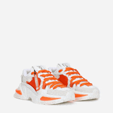 a pair of white and orange sneakers with a tag that says ' dolce & gabbana '