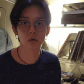 a young man wearing glasses and a necklace is standing in front of a record player