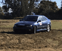 a blue car is driving through a muddy field