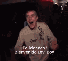 a man wearing a camel sweater is dancing in a dark room with the words felicidades bienvenido levi boy below him