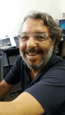 a man with glasses and a beard is smiling at the camera