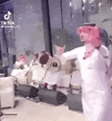 a man in a pink mask is dancing in a room with a lot of drums .