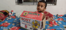 a baby is sitting in a sony high speed fan box