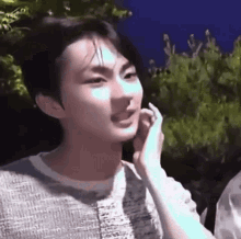 a young man is talking on a cell phone while a woman holds his hand to his face .