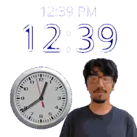 a man with glasses stands next to a clock that says 12:39 pm