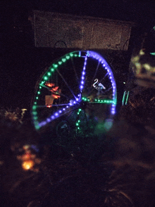 a ferris wheel with green and purple lights on it