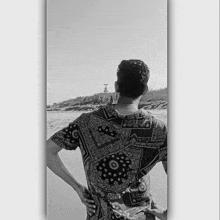 a man in a paisley shirt stands on the beach