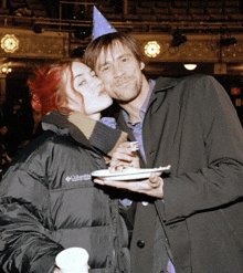 a woman wearing a columbia jacket is kissing a man