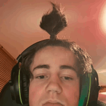 a young man wearing headphones with a bun on his head