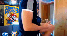 a man is holding a controller in front of a super mario 3 poster