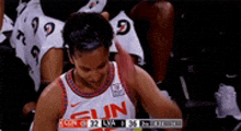 a basketball player in a sun jersey is sitting in the stands during a game .