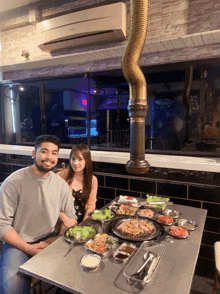 a man and a woman sit at a table with plates of food on it