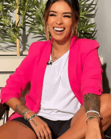 a woman wearing a pink blazer and a white shirt has a tattoo on her wrist that says ' i love you '