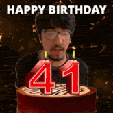a man blowing out candles on a cake that says happy birthday