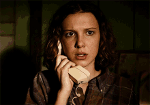 a woman is talking on a telephone with a surprised expression on her face