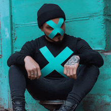 a man wearing a black shirt with a green x on it