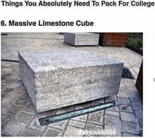 a massive limestone cube is sitting on a sidewalk next to a brick wall .