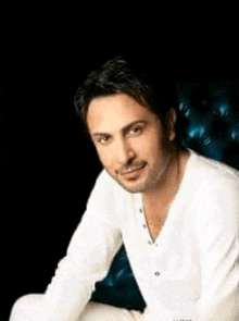 a man in a white shirt is sitting on a blue leather chair