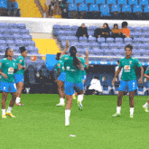 a group of female soccer players on a field with one wearing a green shirt that says ' brasil ' on the back