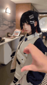 a person is making a heart shape with their hand in front of a girl with a x on her hair