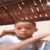 a young boy is making a funny face while sitting on a couch in front of a wooden wall .