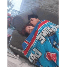 a boy and a girl are sleeping on a couch under a blanket .