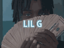 a man holding a stack of money with lil g written on the top