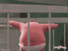 a pink cartoon character is standing behind a fence .