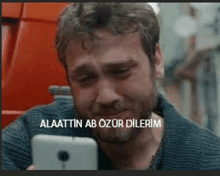 a man with a beard is crying while looking at his phone