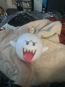 a person is holding a toy ghost with a crown on its head