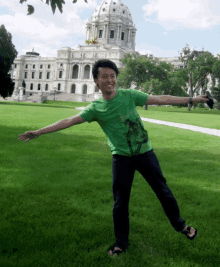 a man in a green shirt stands in front of a building