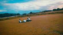 a group of people sitting on the ground in a field