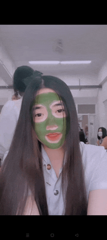 a girl with long hair is wearing a green face mask .