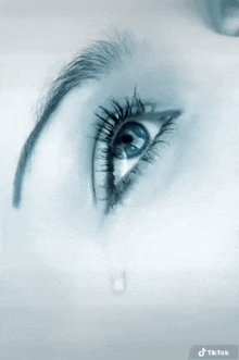 a close up of a woman 's eye with a single tear coming out of it