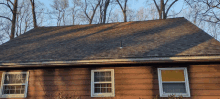 a house with a roof that is covered in shingles and trees in the background