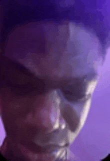 a close up of a person 's face with a purple background and sunglasses .