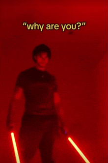 a man holding two lightsabers in front of a red wall with the words " why are you " above him