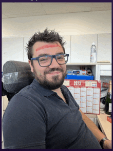 a man with a bandage on his forehead is sitting in front of a calendar for 2023