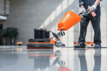 a man is cleaning a floor with an orange machine