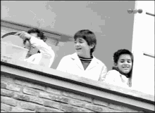 a black and white photo of a group of children on a balcony with the letters rc on the bottom right