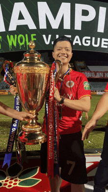 a man in a red shirt is holding a trophy in front of a sign that says wolf league