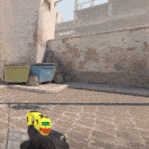 a person holding a yellow toy gun with a green and red sticker on the back